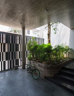 a bike is parked in front of a building with plants on the outside and stairs leading up to it