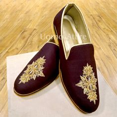 a pair of maroon and gold embroidered shoes