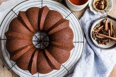 a bundt cake sitting on top of a cooling rack next to bowls of cinnamon sticks