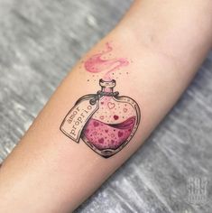 a small bottle filled with pink liquid on top of a woman's arm and the word