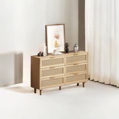 an empty room with a dresser and pictures on the shelf next to it in front of a window