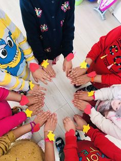 a group of children standing in a circle with their hands on top of each other