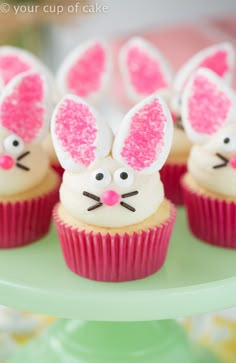 some cupcakes with bunny ears on them are sitting on a green plate and one has pink frosting