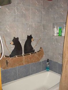 two bears are sitting in a canoe on the wall of a bathtub that is decorated with tile