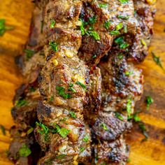 some meat is sitting on top of a wooden cutting board with parsley around it