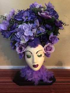 a mannequin head with purple flowers on it's head and eyes painted green