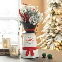 a snowman planter sitting on top of a table next to a christmas tree