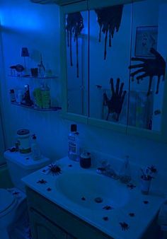 the bathroom is lit up with blue light and creepy handprints on the walls