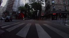 a city street with buildings and cars on it at sunset or sunrise, as seen from the crosswalk