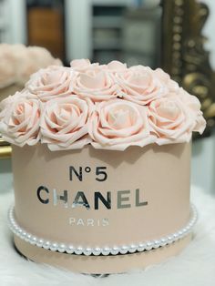 a chanel hat with pink roses and pearls on the top is sitting on a white furnishing