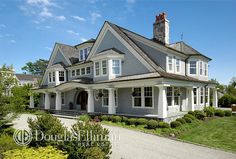 a large gray house with white trim on the roof and windows, surrounded by greenery