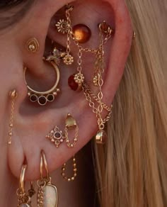 a close up of a person's ear with various jewelry on it, including earrings and rings