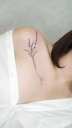 a woman with a flower tattoo on her shoulder and chest is laying down in bed