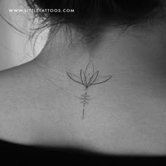 a woman's back neck with a single flower tattoo on it