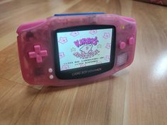 a pink game boy advance sitting on top of a wooden table