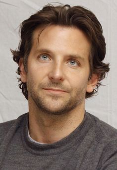 a close up of a person wearing a gray shirt and looking at the camera with a serious look on his face