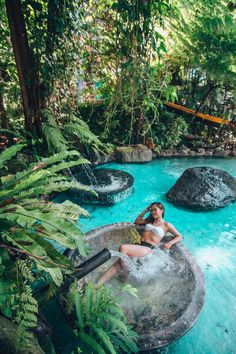 a woman sitting on top of an inflatable pool surrounded by trees and plants