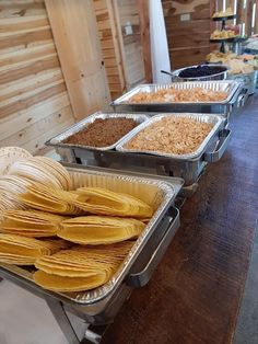 several trays of tortillas are lined up on a table