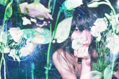 a woman is surrounded by flowers and plants