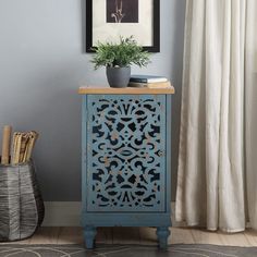 a blue cabinet sitting next to a window with a plant on top of it in front of a white curtain