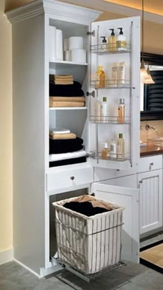 a bathroom with white cabinets and shelves filled with personal care items, including a laundry basket