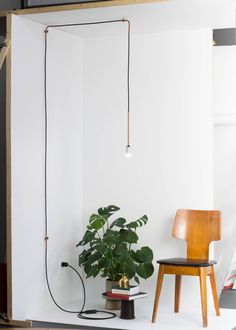 a white room with a chair and a potted plant