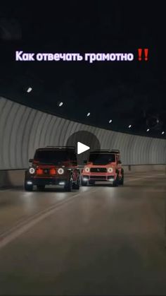 two cars driving down the road in front of a tunnel with an advertisement on it