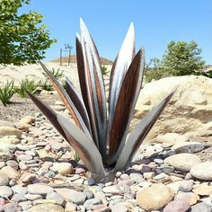 a metal plant sitting on top of a pile of rocks