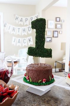 a birthday cake with the number one on it and strawberries in front of it