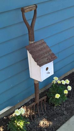 a bird house made out of tree branches with a shovel stuck in it's mouth