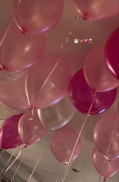 pink and white balloons are hanging from the ceiling