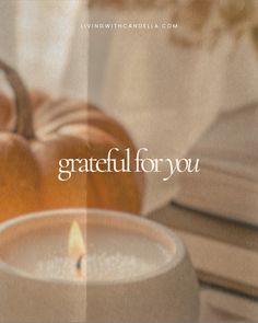 a white candle sitting on top of a table next to a pile of pumpkins