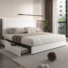 a white bed with drawers underneath it in a room next to a large window and sliding glass doors