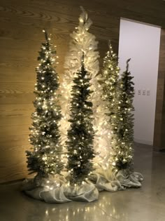 three artificial christmas trees with white lights on them