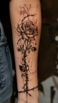 a woman's arm with a rose on it and barbed wire around the wrist