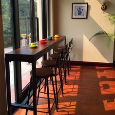 a long table with four stools in front of it next to a large window