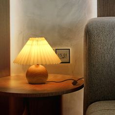 a lamp sitting on top of a wooden table next to a gray chair in a room