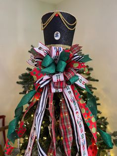 a christmas tree decorated with ribbons and a crown on it's head is shown