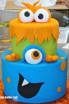 a blue and green cake with monster eyes on it