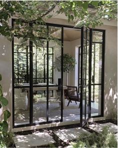 an open glass door leading into a patio area with chairs and trees in the background