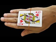 a person's hand holding a playing card in their left hand, with an orange string attached to it