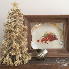 a small christmas tree sitting on top of a wooden shelf next to a plate and silver ornament