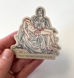 a hand holding a sticker with an image of a woman sitting on a bench