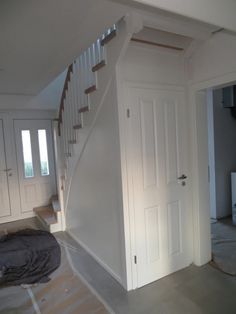 an empty room with white walls and stairs in the background, there is a rug on the floor next to the door