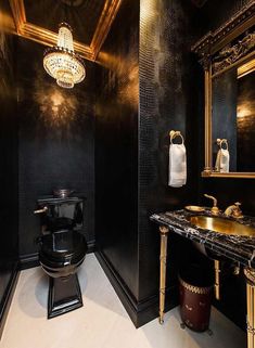 a bathroom with black walls and gold trim around the sink, toilet and vanity area