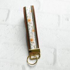 a keychain with flowers on it is hanging from a hook in front of a white wall