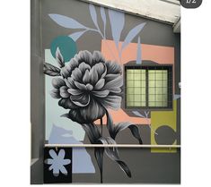 a large flower painted on the side of a building next to a window with bars