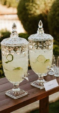 two glasses filled with water sitting on top of a wooden table next to each other