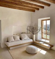 a living room with white furniture and wood beams on the ceiling, along with a large window