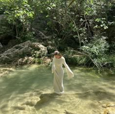 a woman in a white dress is standing in the water